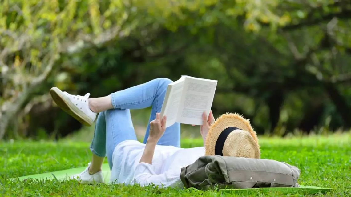 Mujer-tumbada-en-la-hierba-leyendo-un-libro-de-RRHH-en-el-parque-1140x640