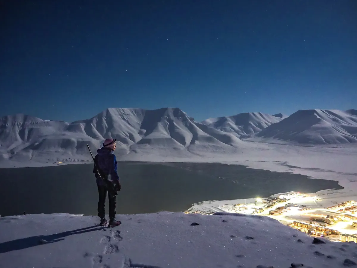 writer-looks-over-lit-town-mountain-3268344