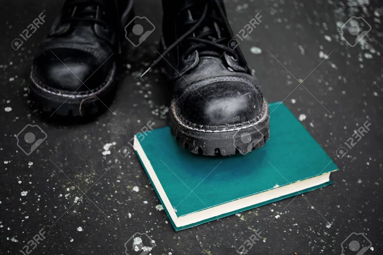 64540683-pie-con-botas-ásperas-pisando-un-libro-puesto-en-el-suelo-primer-plano-de-enfoque-selectivo